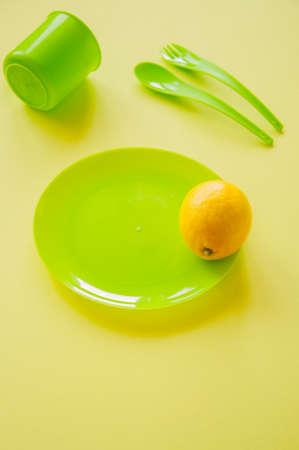 Yellow ripe lemon and light green colored tableware on a yellow background.の写真素材
