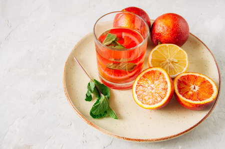 Glass of citrus infused water with mint. Blood oranges and lemon in a plate on a white background. Overhead view and copy space.の写真素材