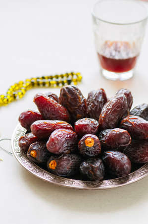 Medjoul - dried dates or kurma in a vintage plate and tea. 