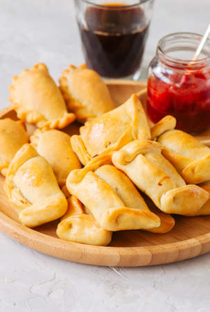 Two types of empanadas on a wooden plate with ketchup