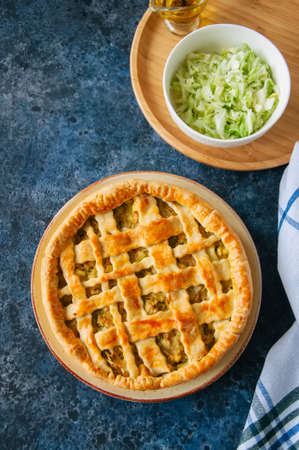 Homemade young cabbage pie from flaky dough  served on a plate. blue stone background.  Top view.