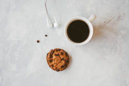 A cup of coffee and a chocolate chip cookie ona white stone background. Top view. Flat lay.の写真素材