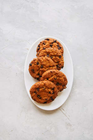 American chocolate chip cookies  in a white plate on a white stone background. Top view and copy...