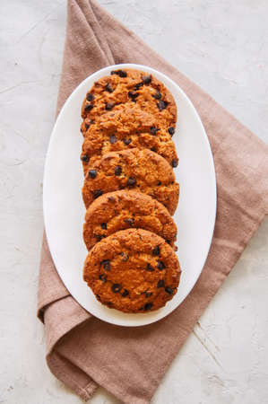 American chocolate chip cookies  in a white plate on a white stone background. Top view and copy...