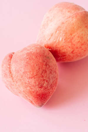 Two fresh ripe peaches on a pink background. Organic food concept. Close up.の写真素材