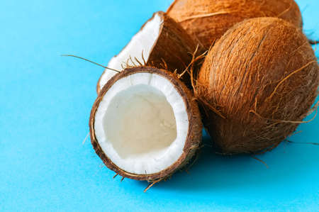 Whole and halfs of coconuts on a blue background. Top view and copy space.の写真素材