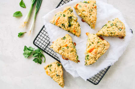 Savory scones with feta mozarella and green herbs on a wire rack. White stone background.の写真素材