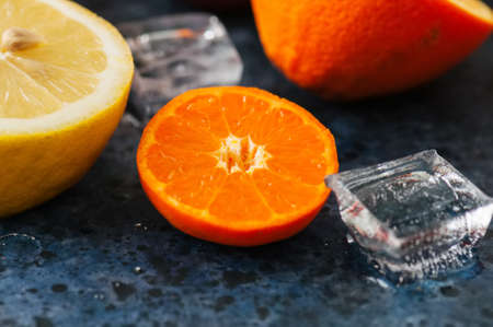 Mix of fresh ripe citrus fruits as blood oranges, mandarines, lemons  with ice cubes on a blue stone background. Top view.の写真素材