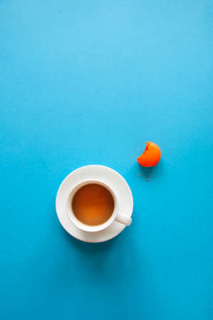 A cup of tea and macaron cookies on a blue background. Top view and copy space,の写真素材