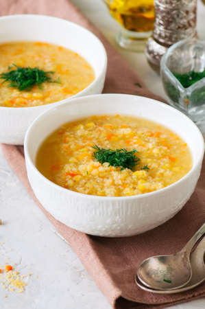 Lentil and bulgur soup puree in a white bowl on a white stone background.の写真素材