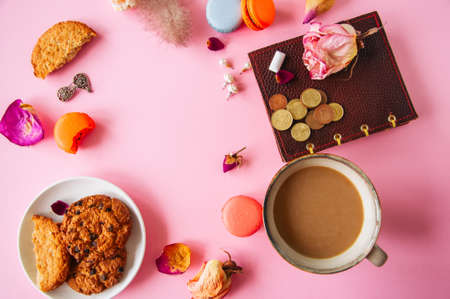 Flat lay of femenine things cookies coffee pearls flowers on a pknk background. Top view.