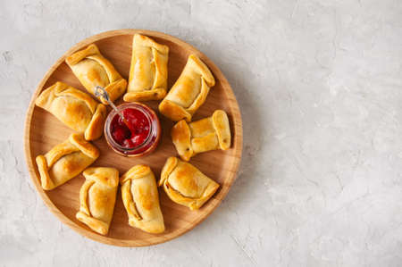Top view of chilean empanadas on a wooden plate with ketchup. White stone background.の写真素材