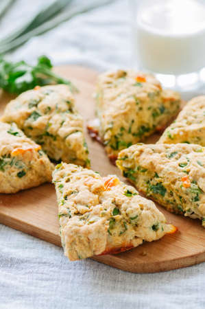 Savory scones with feta and mozarella and green herbs on a wooden board.の写真素材