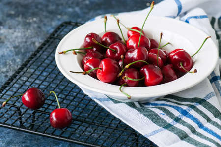 Fresh ripe red cherries in a white plate on a wire rack. Close up. Organic food concept.の写真素材