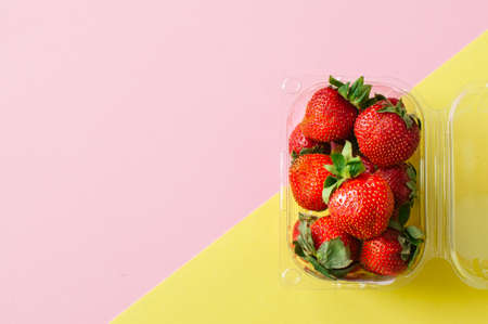 Fresh ripe strawberries in plastic container on duotone background. Top view and copy space. Organic food concept.の写真素材