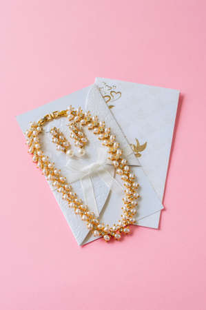 Wedding concept. Invitation cars and pearl necklace on a pink background.の写真素材