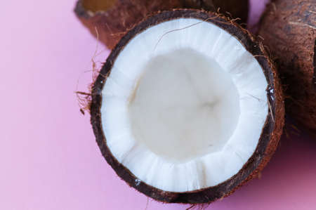Half of coconut on pink background. Close up.