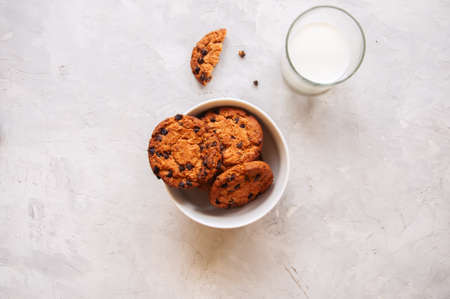 American chocolate chip cookies with glass of milk on a white stone background. Top view and copy...