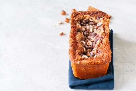 Pumpkin espresso bread with hazelnuts on a blue napkin on a white stone background. Top view and...