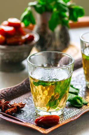 Traditional moroccan mint tea with dates on a vintage tray. White stone background. Close up.の写真素材