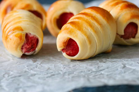 Pigs in a blanket on a baking paper. Close up. Fast food, beer snack or lunch box food concept.の写真素材