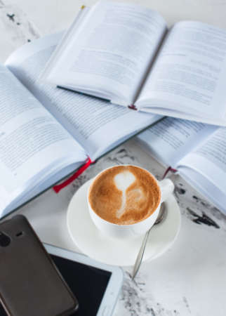 Group of opened books, cup of coffee, tablet and smartphone on a gray background, Overhead view.の写真素材