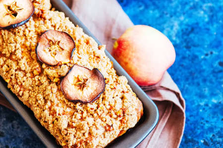 Homemade apple crumble cake served on a wire rack on a white sto