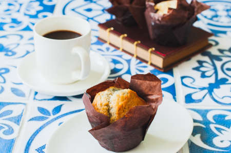 A cup of coffee and muffins on a blue kitchen working place. Close up.