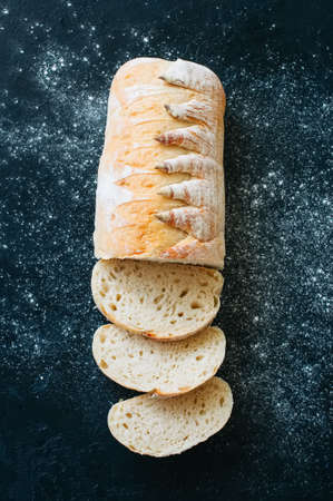 Homemade white sourdough bread with flour on a black background. Top view.