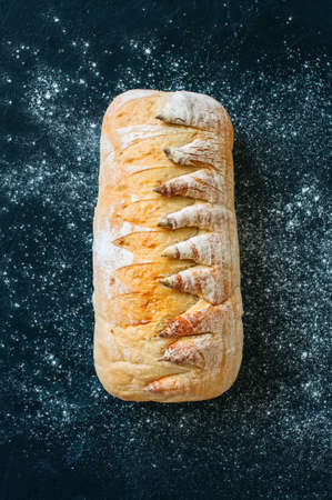 Homemade white sourdough bread with flour on a black background. Top view.