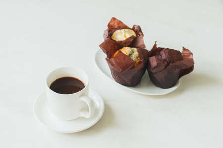 A cup of coffee and three  muffins on a white background. Close up.