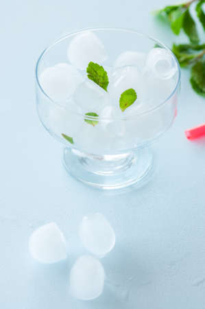 Ice cubes in a glass bowl with mint leaves. Blue background.の写真素材