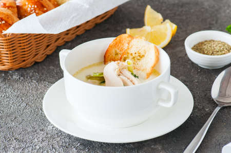Creamy vegetable soup with chicken and croutons in a white bowl on a gray background.の写真素材