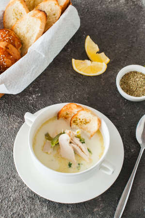 Creamy vegetable soup with chicken and croutons in a white bowl on a gray background.の写真素材