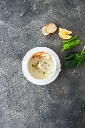 Creamy vegetable soup with chicken and croutons in a white bowl on a gray background.の写真素材