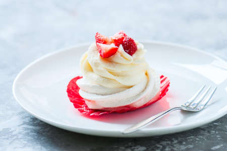 One beautiful pavlova dessert with wipped cream and strawberries in a plate. Close upの写真素材