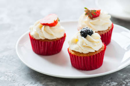 Three delicious cupcakes with berries in a plate. Close up.の写真素材