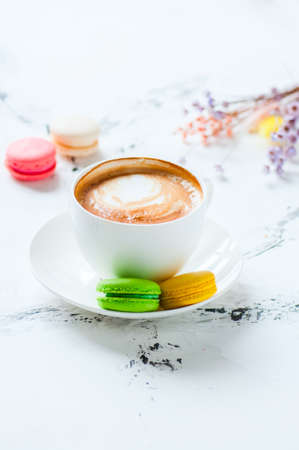One cup of cappuccino and macarons on a white background.の写真素材