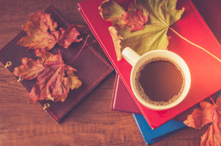 One cup of coffee and books with autumn maple leaves.の写真素材