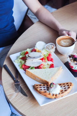 Breakfast concept. Coffee, waffle with ice cream, sandwich and salad with chicken and vegetables.