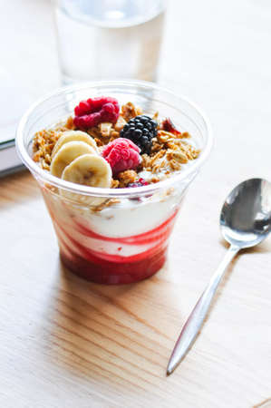 Overnight oatmeal with yogurt, banana slices and berries on a table. Close up.