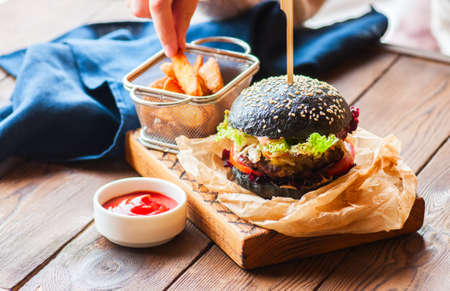 Black burger in a parchment paper on a wooden background.の写真素材