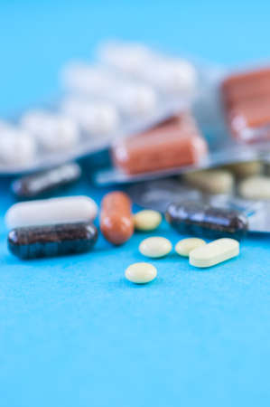 Close up of assorted medicine pills and tablets on a blue background.