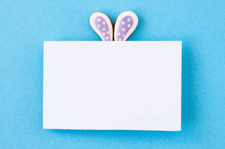 Easter background concept. Easter bunny ears under white empty paper on blue background.の写真素材