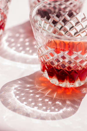 Red wine in a glass and beautiful reflection from glassware on a pink background.