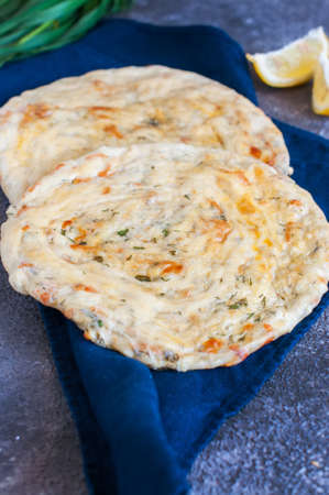Homemade flatbreads with leek on a wooden plate.