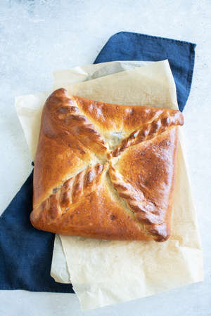 Freshly baked meat pie on a parchment paper on table background. Pie with meat and mushrooms. Top view. Rustic styleの写真素材