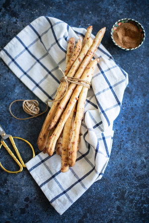 Grissini - Italian bread sticks with dried herbs on a wooden background.