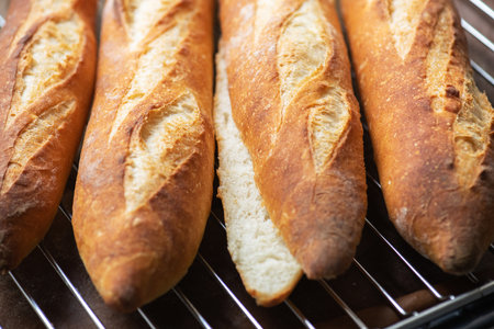 Batch of freshly baked baguettes background, whole and cutted baguettes. Close up.の写真素材