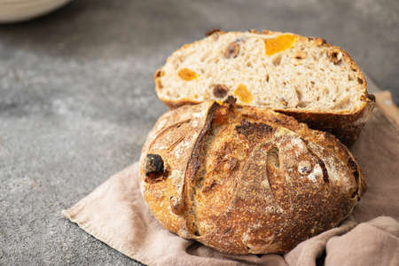 Halved sourdough dessert bread with dried apricots and walnuts on a napkin. Close up.の写真素材